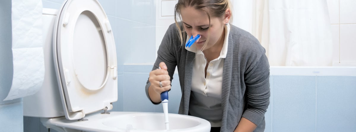 Mujer limpiando un váter con pinza en la nariz