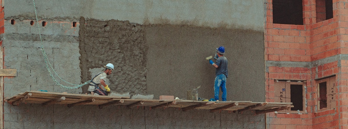 Dos obreros en un andamio revocando una pared