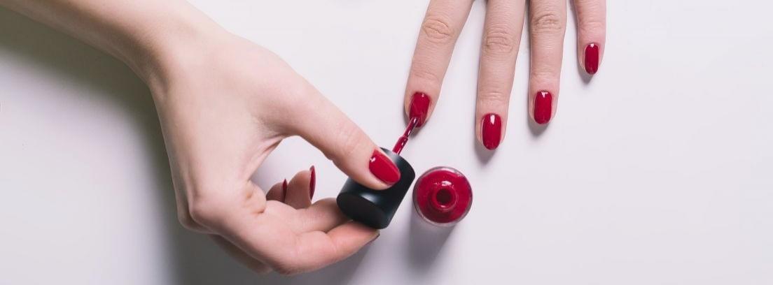 Manos de mujer pintándose las uñas de rojo