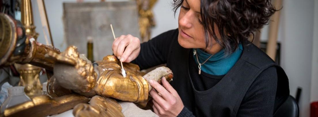 Mujer restaurando una pieza de metal antiguo