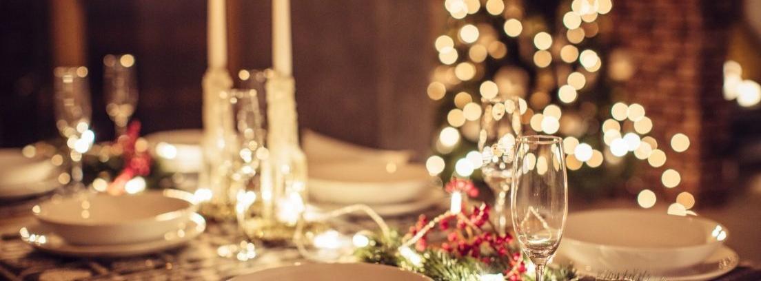 Plato blanco sobre plato gris y servilleta con cubiertos de bronce con adorno navideño