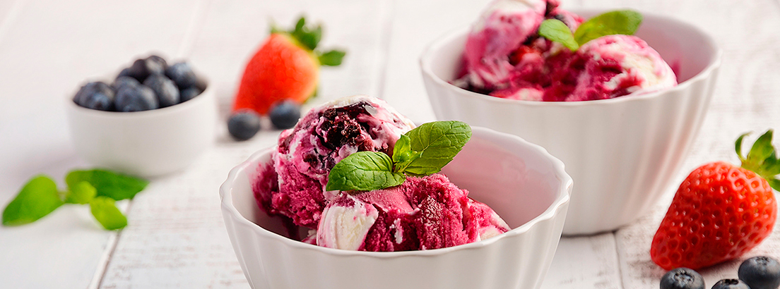 dos cuencos de helado de arándanos y fresas con hojas de albahaca