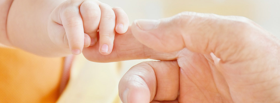 Mano de bebé agarrándose a la mano de un adulto con apego, una de las ventajas del método canguro