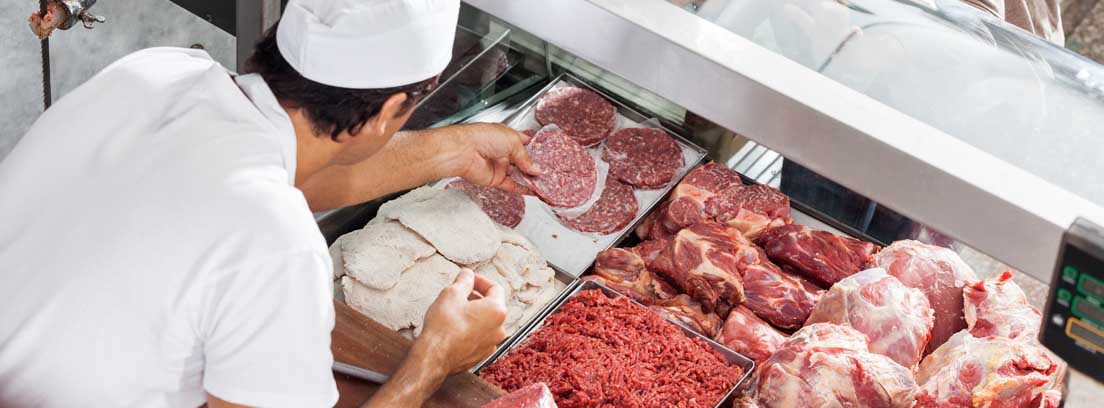 Mujer frente a mostrador con diferentes tipos de carnes.