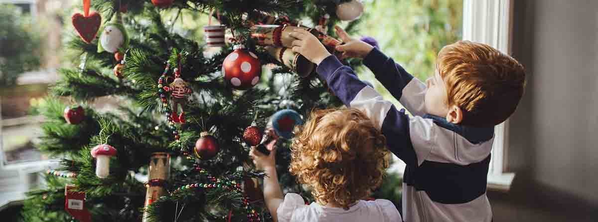 niños adornando árbol de navidad