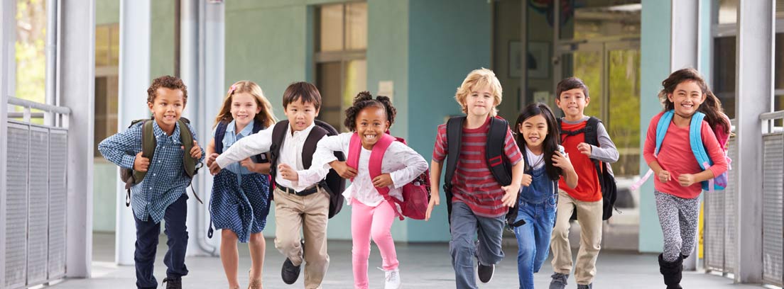 Grupo de niños con mochilas corriendo por un pasillo