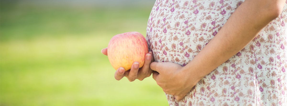 Mujer embarazada sosteniendo una manzana