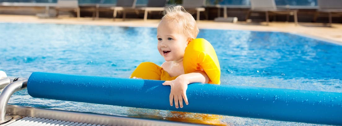 Niño dentro de una piscina sujetándose en un enrollador de cubiertas para piscina