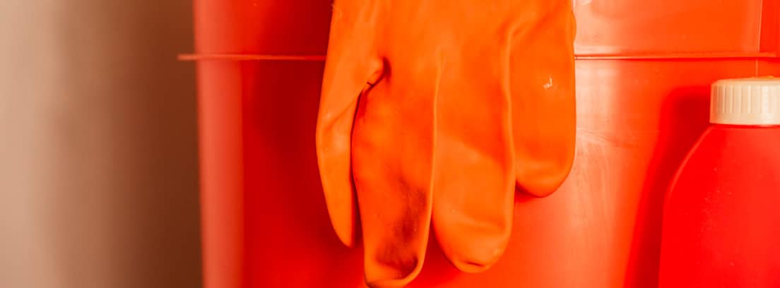 Cubo naranja con guante de látex y bote de lejía