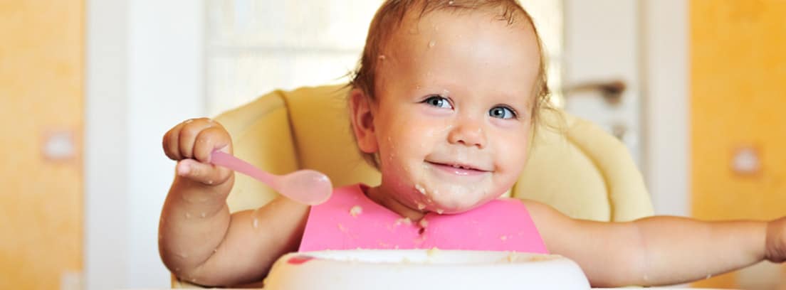 Bebé sonriente comiendo puré