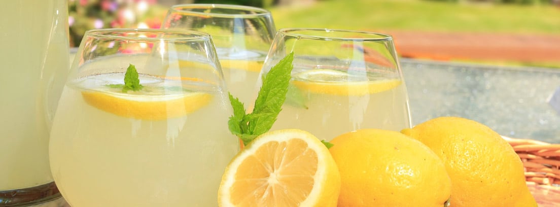 Limones y limonada en vasos sobre una cesta