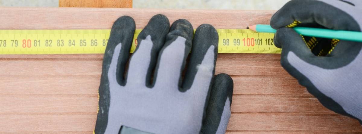 persona con guantes midiendo madera con un metro