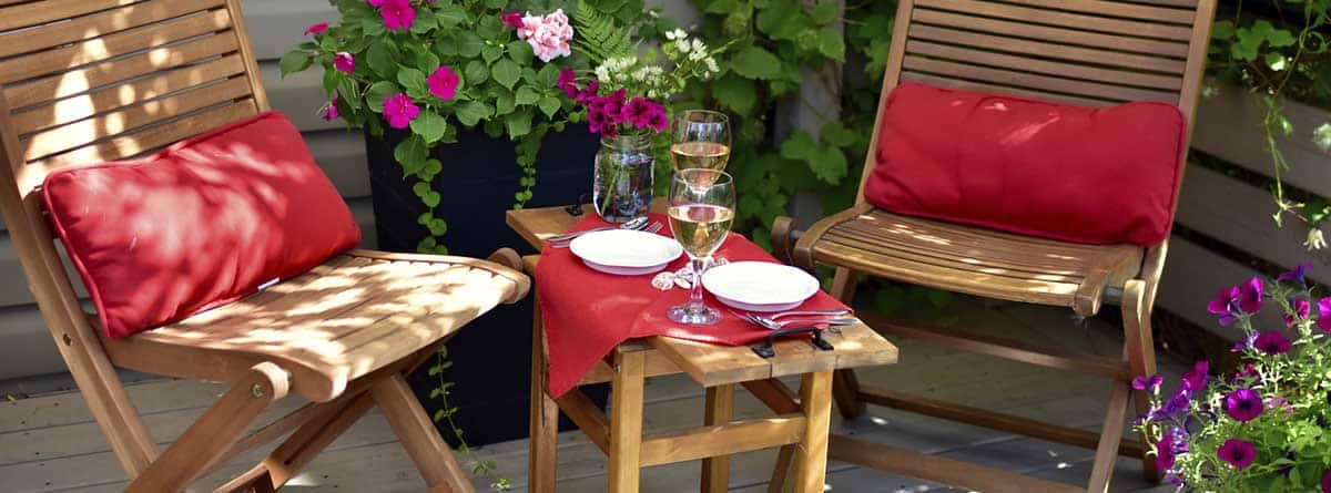 Mesa de madera en el jardín con mantel rojo y 2 sillas