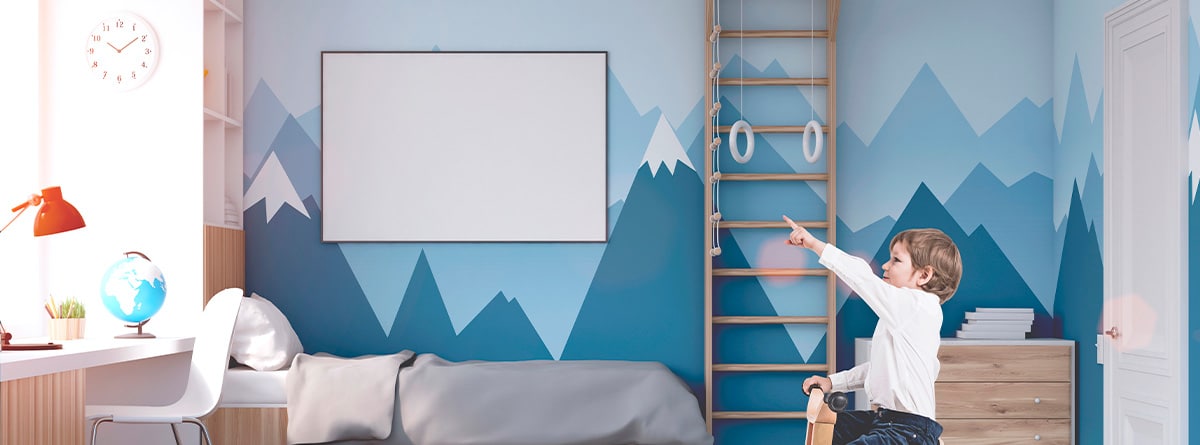 niño en su habitación infantil co la pared pintada con montañas