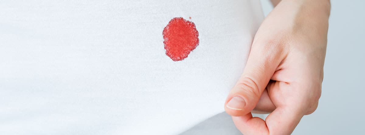 Mancha de esmalte rojo sobre una camiseta de algodón