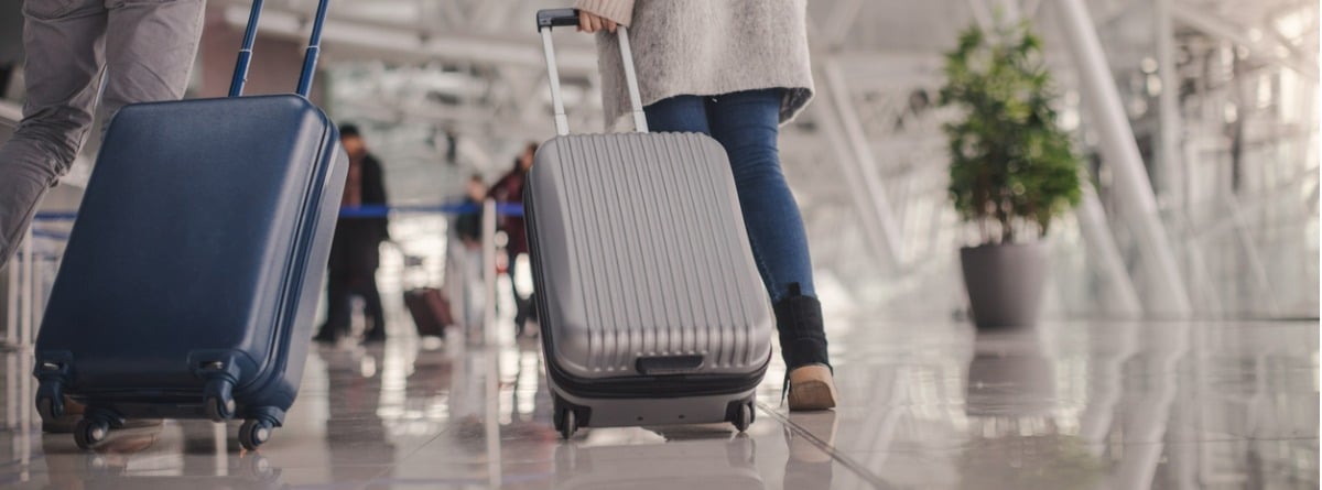 dos personas con maletas de mano por el aeropuerto