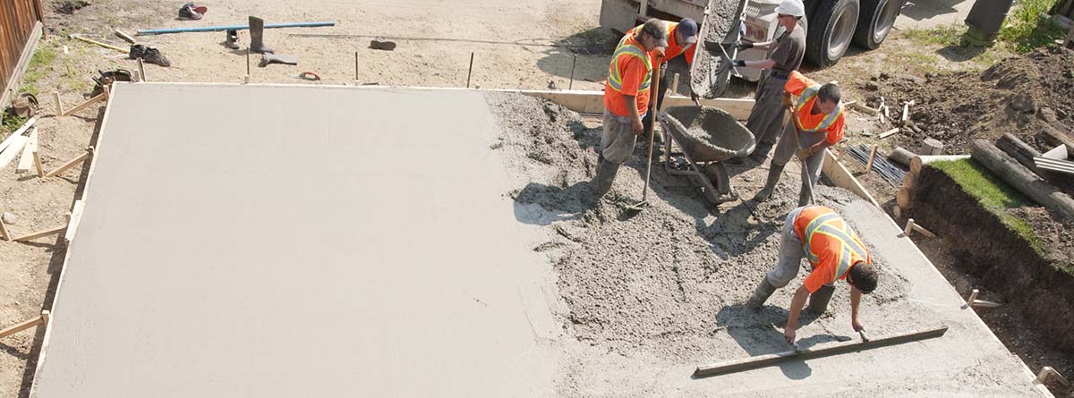 Trabajadores de la construcción poniendo cemento en el suelo