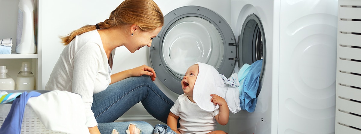 Mujer y niño junto a una lavadora para lavar la ropa del bebé
