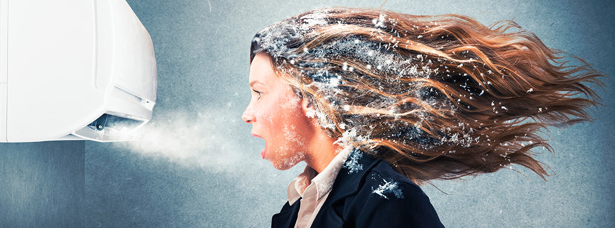 Mujer congelada frente a un aire acondicionado