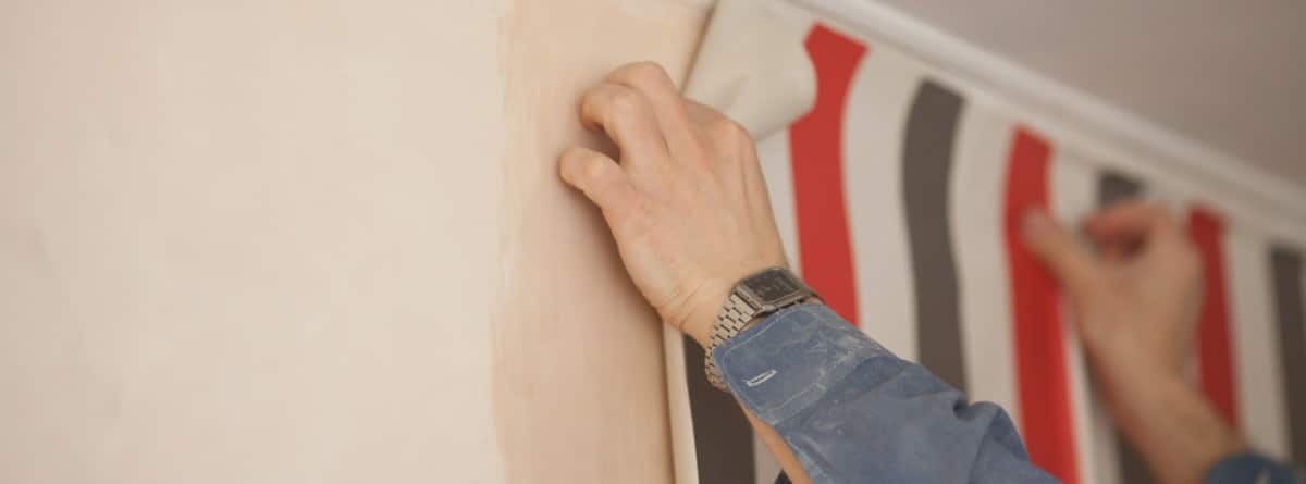 persona colocando papel pintado sobre pared de gotelé