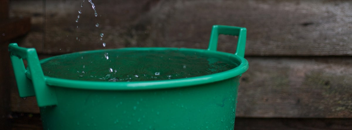 Caldero recogiendo agua de lluvia de un canalón