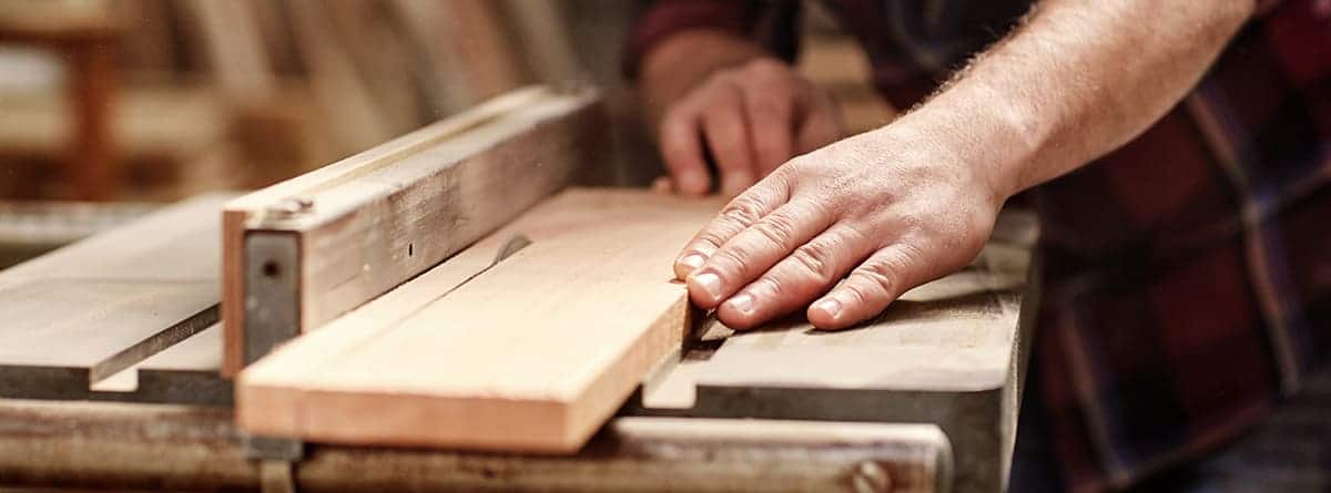 hombre cortando una tabla de madera