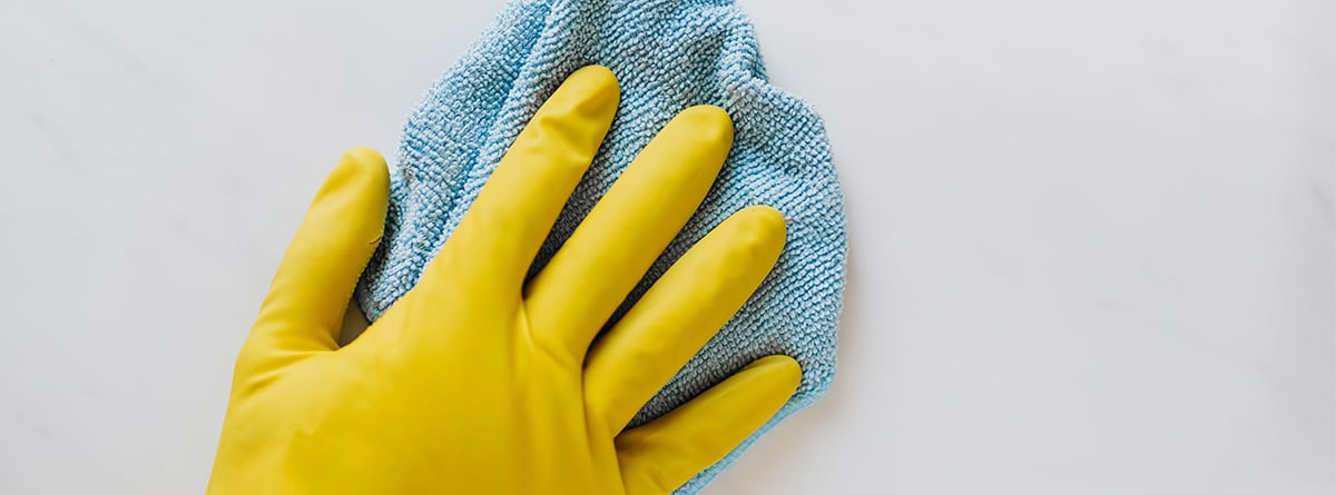mano con guante amarillo limpiando una pared
