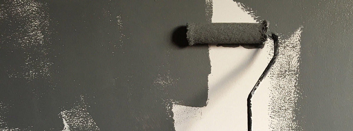 un rodillo pintando la pared de gris