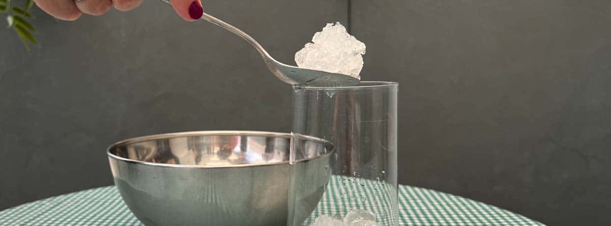 mano echando hielo triturado en un vaso con una cuchara