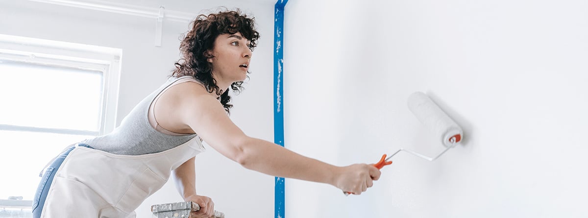 mujer pintando la pared con un rodillo