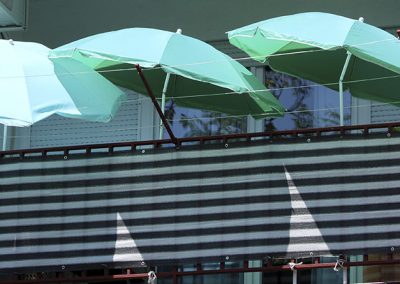 Tres sombrillas redondas verdes en un balcón