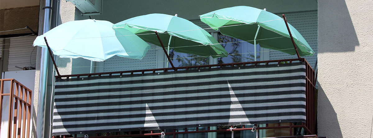 Tres sombrillas redondas verdes en un balcón
