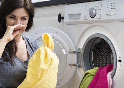 Mujer tapándose la nariz junto a la lavadora
