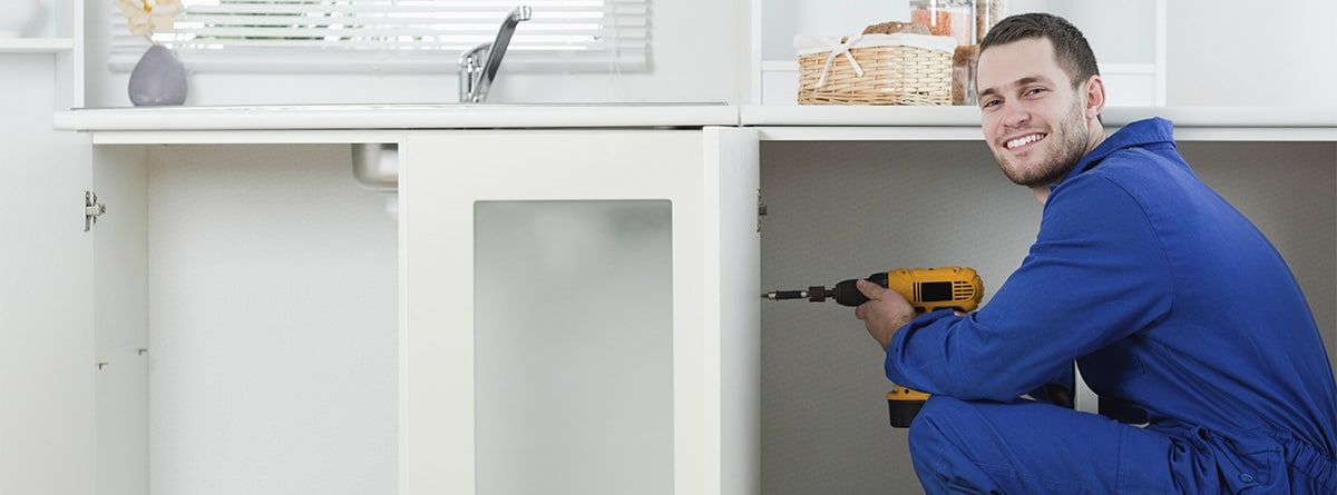 Hombre con taladradora en la mano haciendo cambios en una cocina.