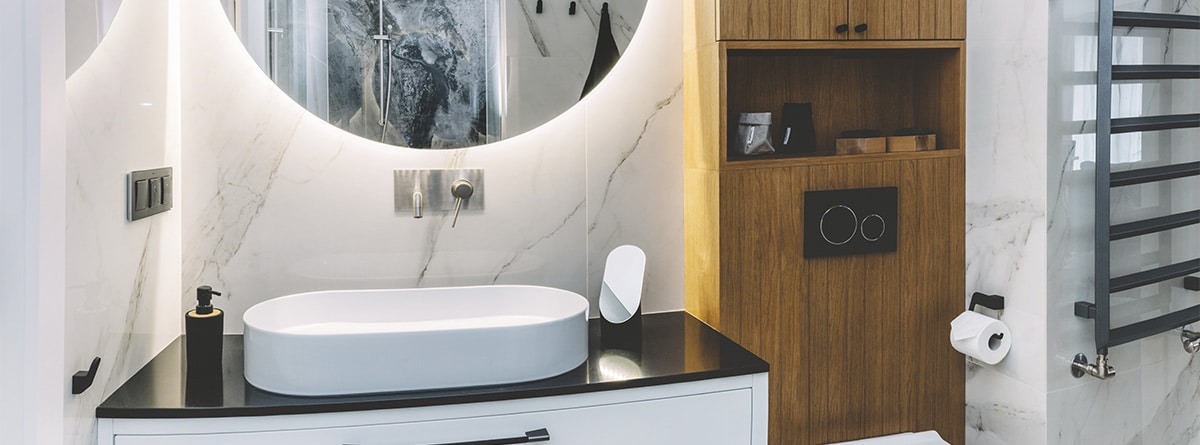 Cuarto de baño con decoración bold, con un espejo circular retroiluminado en el lavabo.