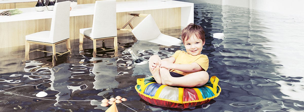 Cocina inundada y un niño sonriente flotando encima de un flotador de colores