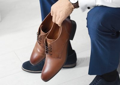 Hombre sentado con un par de zapatos en la mano