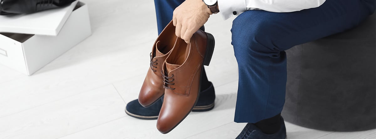 Hombre sentado con un par de zapatos en la mano