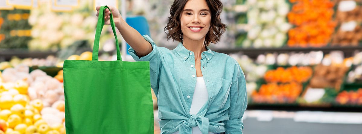 Mujer mostrando una bolsa de rafia en un supermercado