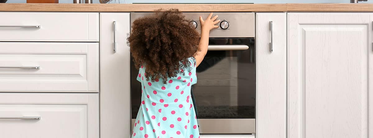 niña pequeña levantando el brazo hacia la altura de la barra de la cocina.