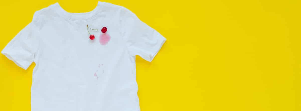 Camiseta blanca con manchas de cereza sobre fondo amarillo.