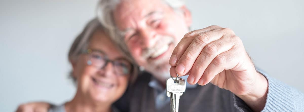 Una pareja senior se abraza con una llaves en la mano