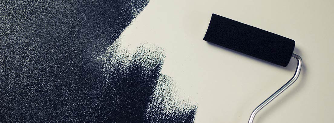 Rodillo con pintura negra pintando una pared