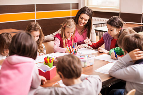 Niños comen alrededor de una mesa en el comedor de un colegio