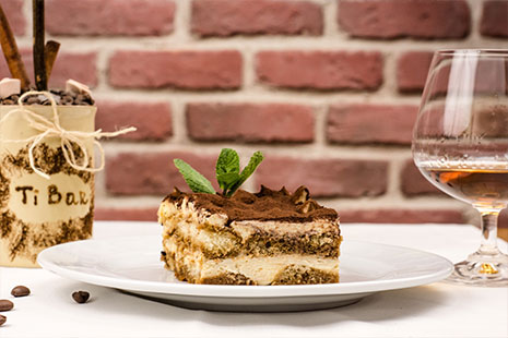 Tarta de tiramisú sobre un plato y copa de licor
