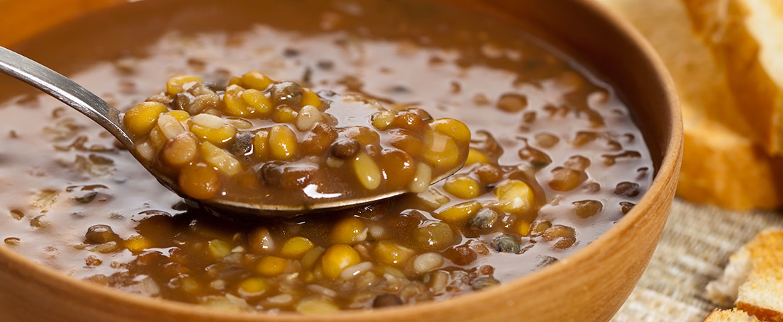 Receta de lentejas caseras Cuchara dentro de una cazuela de barro con estofado de lentejas caseras