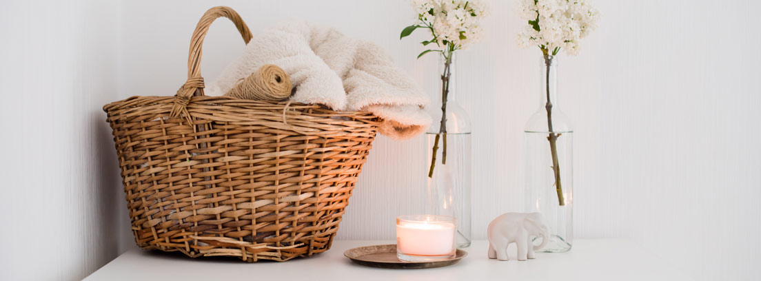 Cestas de mimbre en la decoración - canalHOGAR Cesta con toallas, botellas con flores y velas después de aprender cómo hacer cestas de mimbre para decorar