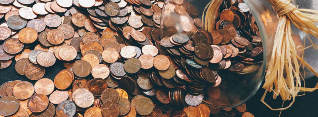 Tarro de cristal junto a monedas antiguas