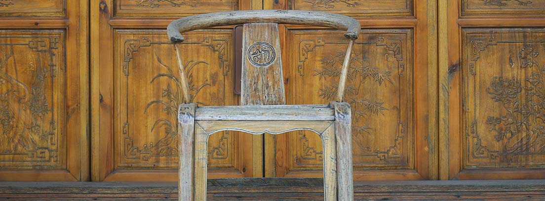 Silla de madera delante de una puerta antigua